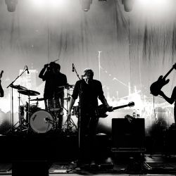 Schwarz-weiß Foto einer vierköpfigen Band von welcher durch die Belichtung nur die Silhouetten erkennbar sind.