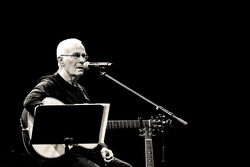 Das schwarz-weiß Bild zeigt Allan Taylor an seiner Gitarre.
