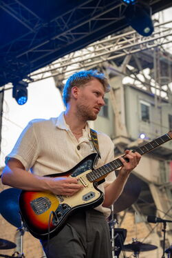 Ein junger Mann mit Gitarre, welcher von unten fotografiert wurde