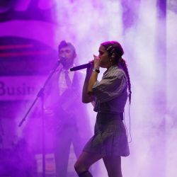 Sängerin in Nebel gehüllt und mit lila Licht. im Hintergrund und unscharf stehen weitere Bandmitglieder.