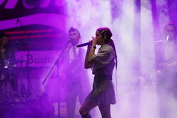 Sängerin in Nebel gehüllt und mit lila Licht. im Hintergrund und unscharf stehen weitere Bandmitglieder.