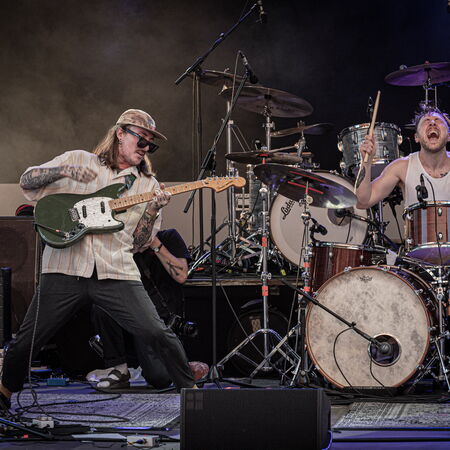 Links auf dem Foto ist der Gitarrist, er steht breitbeinig und leicht nach hinten gelehnt. Rechts ist der Schlagzeuger, welcher aus der bewegung heraus fotografiert wurde.